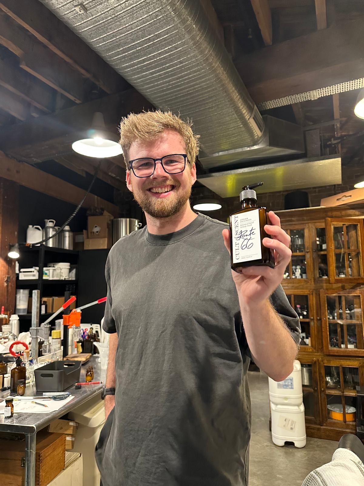 Harry smiling in the scent studio, holding a bottle